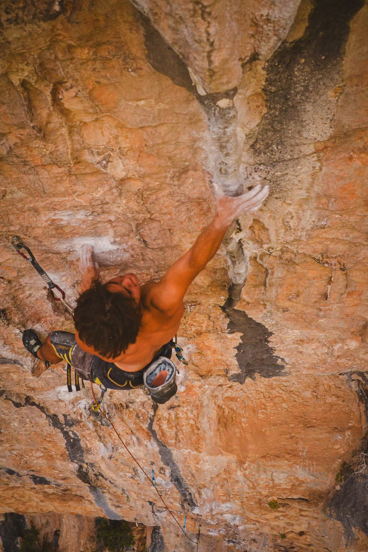 Brandon estirando el brazo hacia una presa en una pared de Siurana