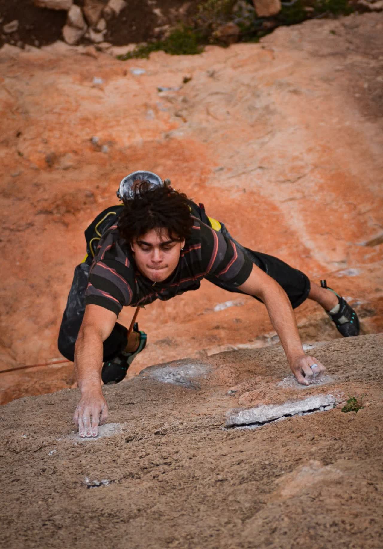 Brandon escalando una placa de roca en Siurana, con magnesio en los dedos