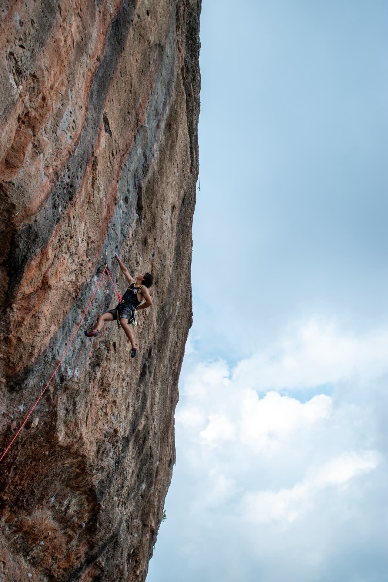 Brandon escalando una pared vertical en Siurana con el cielo de fondo