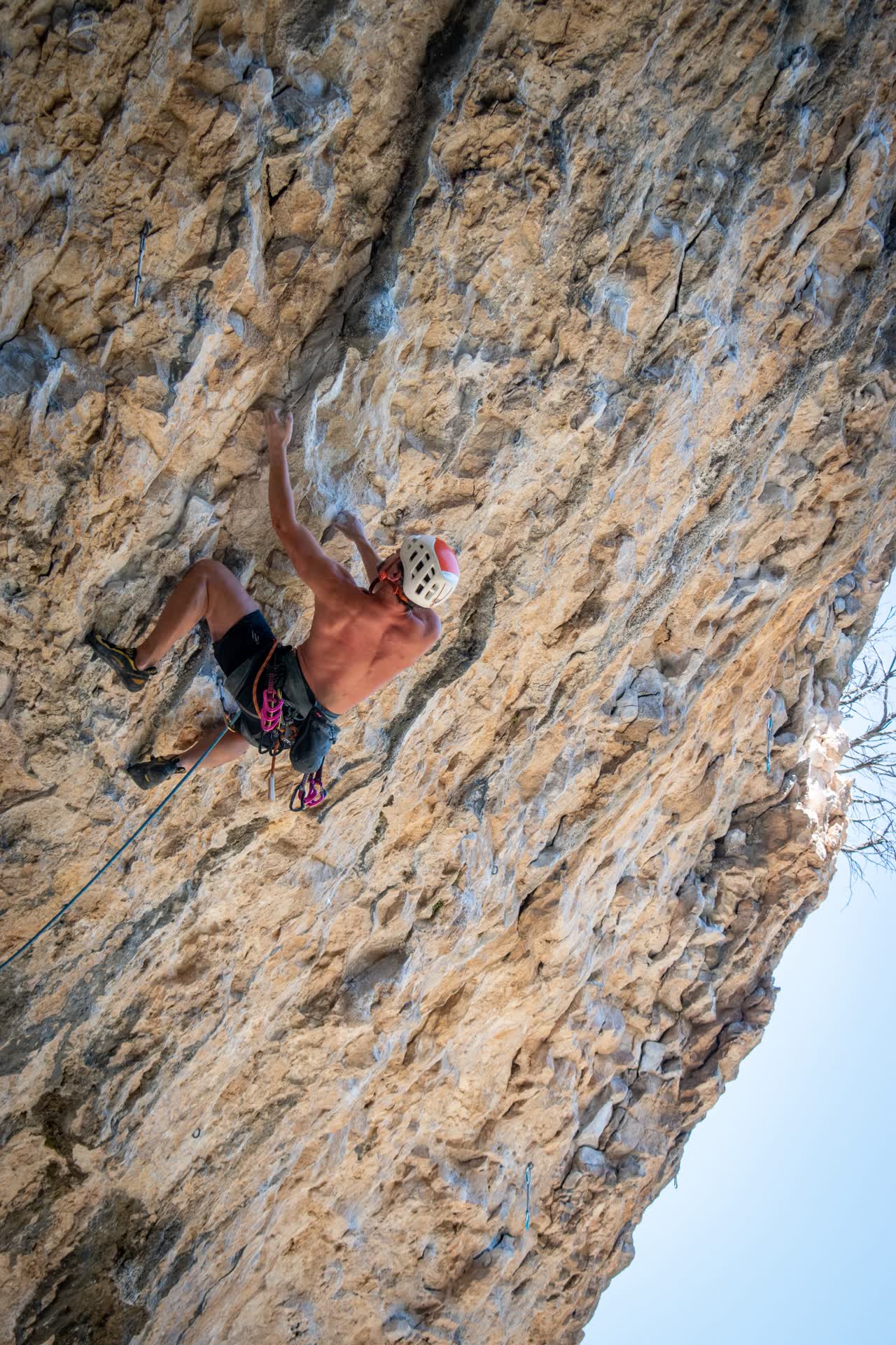 Jose escalando una pared muy inclinada en Siurana, con el brazo estirado hacia una presa
