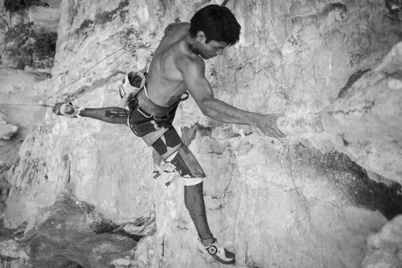 Marce realizando un movimiento dinámico en un techo de roca en Siurana, foto en blanco y negro