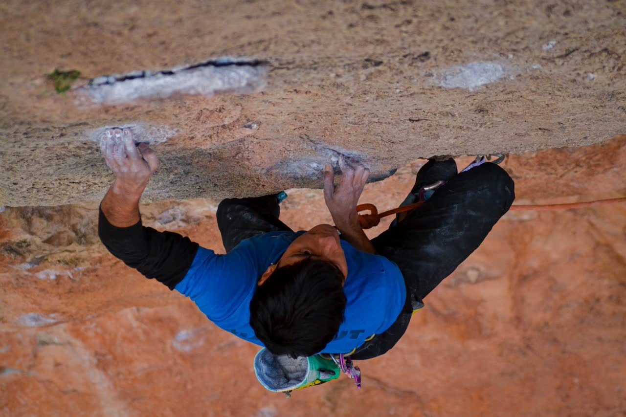 Marce agarrando una hueco con los dedos llenos de magnesio bajo un techo de roca en Siurana
