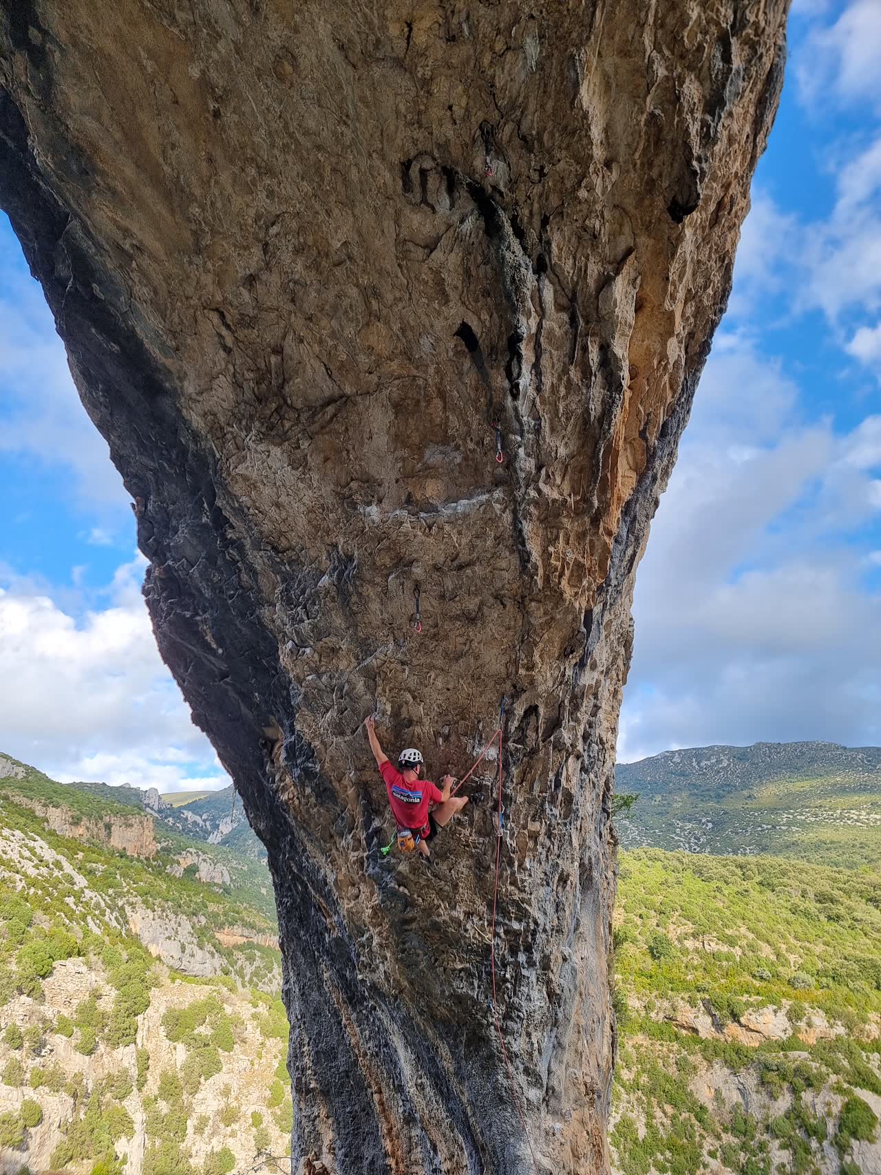 Piero escalando bajo un gran techo de roca en Siurana, con el valle al fondo