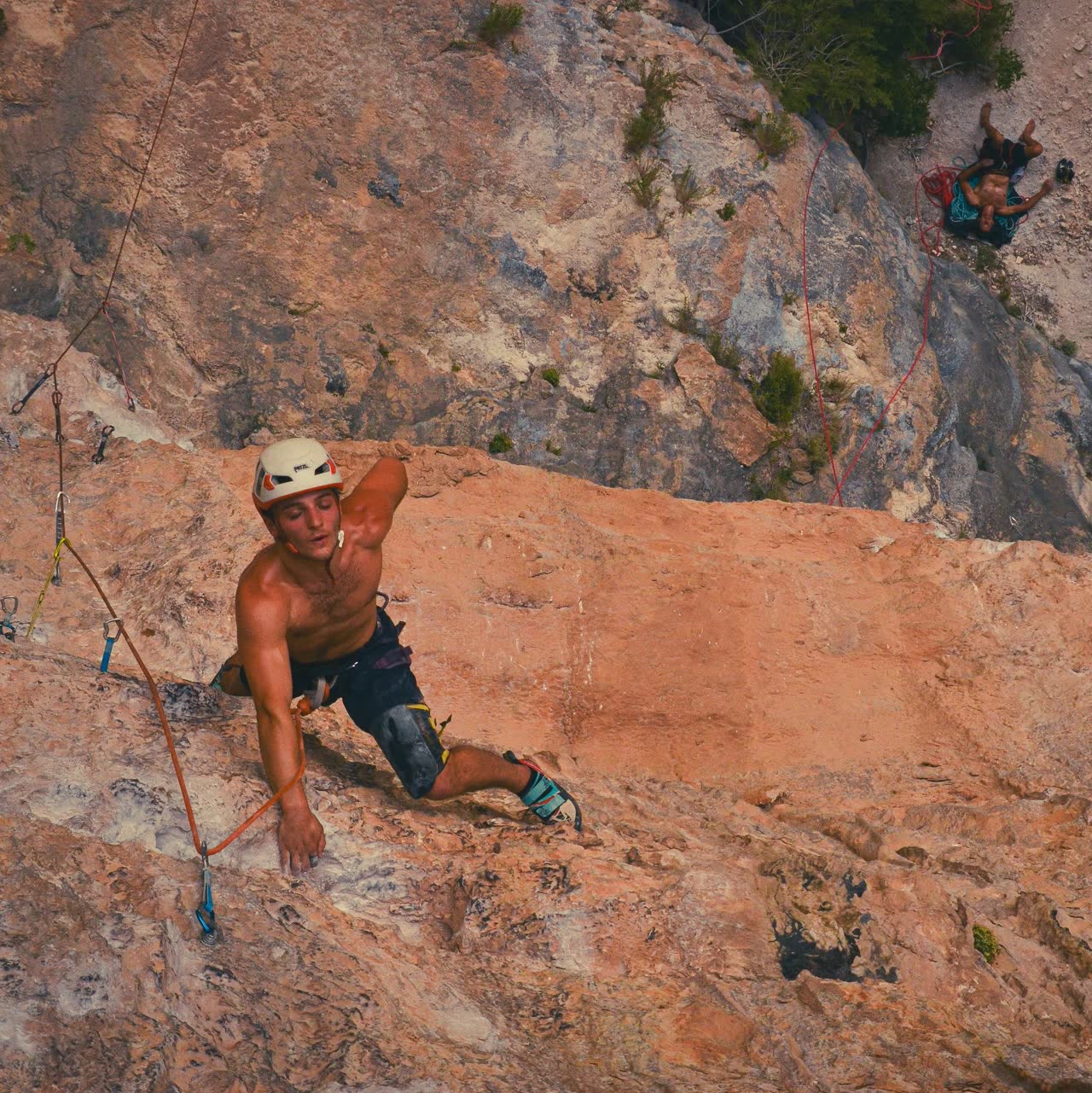 Rocco escalando en Siurana con otros escaladores asegurando desde una repisa al fondo