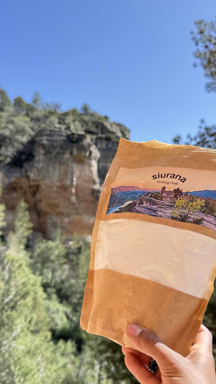 Bolsa de magnesio Siurana Outdoors con la pared de Siurana desenfocada de fondo